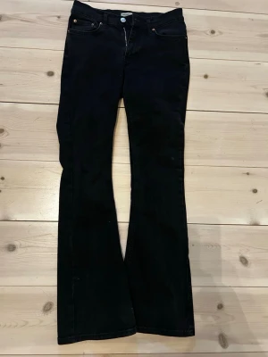 Svarta bootcut jeans med hög midja - Snygga svarta jeans med bootcut passform och hög midja. Klassisk femficksmodell med knapp och dragkedja framtill. Jeansen har en stilren look och är tillverkade i ett mjukt denimtyg som sitter bekvämt. Passar mig som är 164 cm.