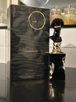 Lattafa His Confession EdP 100ml - Lattafa His Confession Eau de Parfum 100ml med en lyxig svart och guldig flaska, prydd med en unik skulpturformad kork. Doften har tydliga inslag av amber, vanilj, varm krydda, iris, trä och lavendel. Perfekt för dig som gillar djupa och aromatiska parfymer.