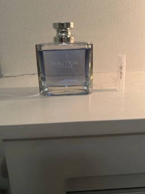 Nautica Voyage parfym  - Fräsch parfym från Nautica, Voyage, i en stilren glasflaska med silverfärgad kork. Doften är blåtonad och flaskan har en modern, fyrkantig form. Perfekt för dig som gillar marina och fräscha dofter.