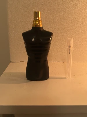 Jean Paul Gaultier Le Male parfym - Ikonisk parfymflaska formad som en manlig torso i svart med guldfärgad spraykork. Flaskan har en modern och stilren design som verkligen sticker ut på hyllan. Perfekt för dig som gillar klassiska dofter med en twist.