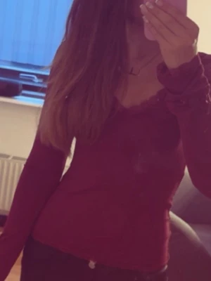Vinröd långärmad topp från Nelly - Vinröd långärmad topp med v-ringning och spetsdetaljer längs halsringningen. Tunn och mjuk i materialet, perfekt att styla med jeans eller kjol. Snygg och enkel design som passar till många olika looks. Använd ca 3 gånger och inga defekter eller skador så i jätte fint skick. Slutsåld på Nelly! Hör gärna av er vid intresse💘🥰