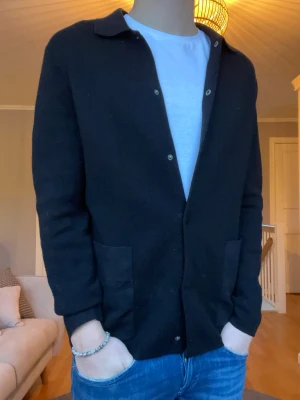 COS overshirt / jacka – svart, storlek S - Stilren overshirt från COS i svart. Tjockare material med strukturerad känsla, perfekt som lätt jacka eller som overshirt över t-shirt eller hoodie. Väldigt clean och tidlös design som funkar till allt.  Passar perfekt för både vår, höst och svalare sommarkvällar. Snygg både uppknäppt och knäppt.  Skick: Mycket bra skick, inga hål eller fläckar Storlek: S Färg: Svart  Nypris låg runt 900–1200 kr.  Pris: 399 kr