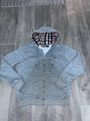 Burberry hoodie  - Riktigt fet hoodie från Burberry. Hoodien har två fickor fram, ribbade muddar och en Burberry logga på bröstet. Perfekt för en chill och stilren look. Den är skön att ha på sig och man kan ha på sig feta outfits med hoodien. storlek S 