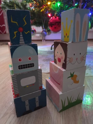 Färgglada träklossar med motiv - Säljer ett set med färgglada träklossar med olika motiv som robot, prinsessa, kanin, kyckling och clown. Klossarna har tryck på alla sidor och kan staplas på olika sätt för att skapa figurer. Perfekt för lek och kreativitet.