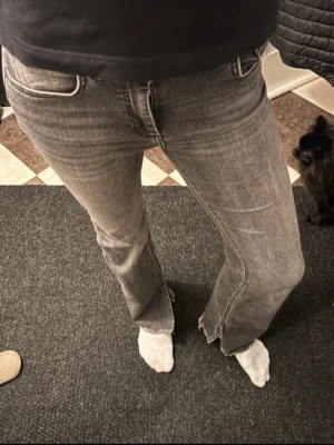 Grå bootcut jeans med låg midja - Säljer ett par grå bootcut jeans med låg midja. Jeansen har klassisk femficksdesign och är tillverkade i ett mjukt denimtyg som ger en avslappnad vibe. Perfekta för dig som gillar en retroinspirerad look.