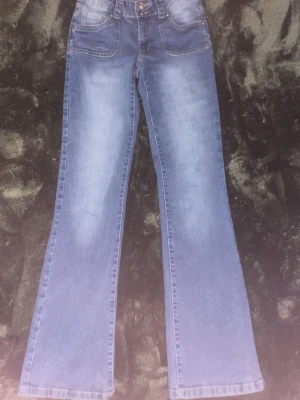 Blå bootcut jeans med hög midja - Snygga blå bootcut jeans med hög midja och klassiska fickor fram och bak. Jeansen har en lätt tvättad look och är tillverkade i mjukt denimtyg. Perfekta för dig som gillar en retrostil med lite utsvängda ben.