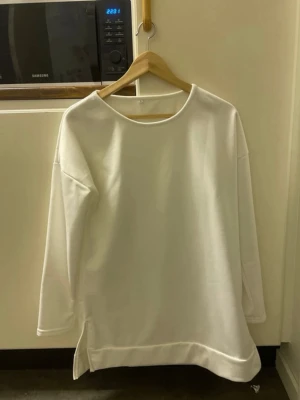 Vit oversized sweatshirt/Tunika - Säljer en vit oversized sweatshirt/Tunika med rund halsringning och långa ärmar. Tröjan har en avslappnad passform och är tillverkad i ett mjukt/Luftigt material som känns skönt mot huden. Perfekt för en chill och stilren look. Känns som den är lite liten i storleken.