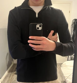 Svart stickad tröja med halv dragkedja - Snygg svart stickad tröja från Jack & Jones med halv dragkedja och hög krage. Tröjan har långa ärmar och ribbade muddar vid ärmslut och nederkant. Perfekt för lager på lager och enkel att matcha med olika outfits. Hör av er vid minsta fundering 