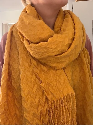 Senapsgul halsduk - Säljer en bred senapsgul halsduk med vågigt mönster. Defekt: se bild nummer 2. Lite ripped på sidan. Fungerar utan problem och håller en varm. Bra när man vill lägga till lite färg i sin outfit! 
