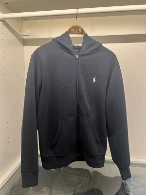Ralph Lauren zip - Mörkblå Ralph Lauren hoodie i storlek S och rätt bra skick, det enda som saknas är en del av zippen och snörena, själva dragkedjan funkar perfekt utan den och förutom detta är den rejält schysst! Fler bilder kan tas vid behöv. Nypris: ca 1800