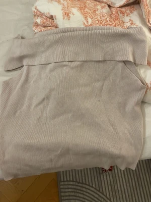 Beige offshoulder ribbad topp - Trendig beige offshoulder topp i ribbat material. Sitter snyggt över axlarna och har en croppad passform som ger en modern look. Har en liten fläck som syns i bild 3 !!!