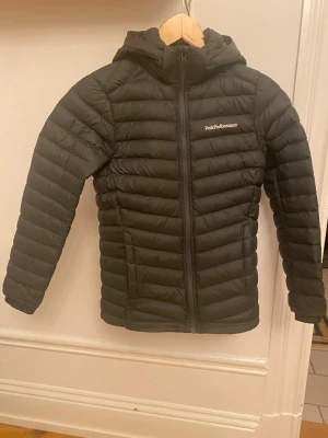 Peak Performance - Lättviktsjacka - Mörkgrön lättviktsjacka från Peak Performance med avtagbar huva. (Ser nöstan svart ut). Knappt använd och aldrig tvättad. Doftar ny fortfarande. 