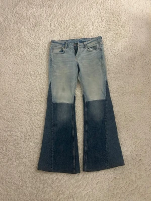 Tvåtonade bootcut jeans i blå denim - Unika tvåtonade jeans med ljusblå överdel och mörkare blå nederdel. Bootcut-modell med utsvängda ben och klassisk femficksdesign. Tillverkade i jeansmaterial och perfekta för dig som vill sticka ut med din stil.