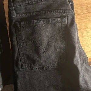 Svarta Levi's 501 jeans straight fit - Svarta Levi's 501 jeans med klassisk femficksdesign och raka ben. Jeansen har silverfärgade knappar och nitar, samt den ikoniska Levi's-sömmen på bakfickan. Materialet är slitstarkt denim i bomull och passformen är straight. WAIST 29 lång 30