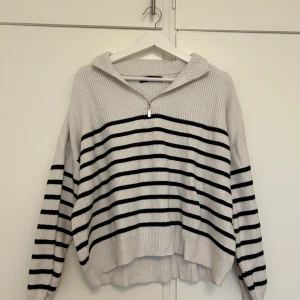 Randig stickad tröja från Mango - Supermysig stickad tröja från Mango i vitt med svarta ränder. Tröjan har en halv dragkedja framtill, huva och ribbad struktur. Perfekt oversized fit med långa ärmar🥰