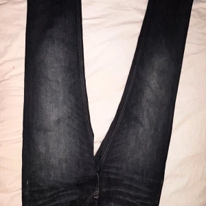 Jack & Jones mörkblå jeans Clark - Snygga mörkblå jeans från Jack & Jones, modell Clark med regular passform. Klassisk femficksdesign, kontrastsömmar och raka ben. Jeansen är tillverkade i slitstarkt bomullsmaterial och har en stilren look som funkar till det mesta.