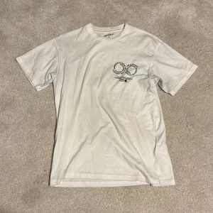 Vit Carhartt WIP t-shirt med tryck - Säljer en vit t-shirt från Carhartt Work In Progress i storlek S. T-shirten har svart grafiskt tryck både fram och bak, klassisk rund hals och korta ärmar. Materialet är mjuk bomull och passformen är normal. 
