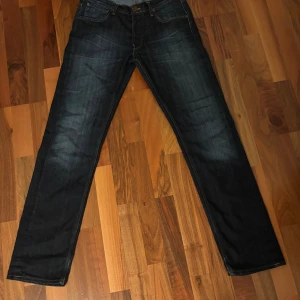 Mörkblå Lee Daren jeans W32 L32 - Mörkblå jeans från Lee. Jeansen har diskreta slitningar och kontrastsömmar. Näst intill perfekt skick med liten slitning på ena bakfickan.