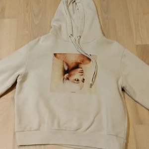 Ariana Grande Sweetener hoodie - Säljer en beige hoodie från Ariana Grande Sweetener tour med tryck fram och låtlista på ryggen. Tröjan har huva med snörning och är långärmad. Mjuk insida och klassisk passform, perfekt för fans av Ariana Grande.