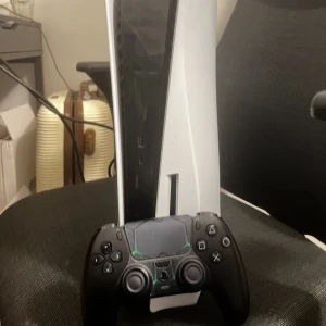 PlayStation 5 - Säljer en PlayStation 5 med svart DualSense-kontroll. Konsolen är i fint skick och fungerar utmärkt, inga synliga repor eller skador. Kontrollen är också i bra skick. Perfekt för dig som vill spela de senaste spelen med hög prestanda och snabb laddning.