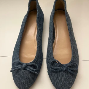Blå denim ballerina H&M storlek 37 - Snygga ballerina från H&M i blå denim-look med rund tå och söt rosett framtill. Skorna har platt sula och är perfekta för dig som gillar en enkel men trendig stil. Materialet är syntet med denimstruktur och insidan är ljusbeige. Jag har bara använt som fåtal gånger 