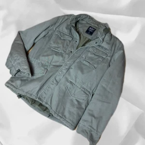 Grå Field Jacket - Grå Field Jacket i storlek L från "Brandit" – enkel att matcha och skön att bära. Ett stilrent val, noggrant utvalt med omsorg av AM Clothing.  📩 Frågor? Hör gärna av dig! 📲 Följ oss här på Plick för fler uppdateringar. ♻️ Tack för att du handlar mer hållbart med AM Clothing!