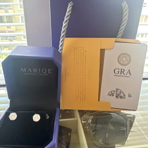 Silver örhängen från Mariqe - Snygga och klassiska örhängen från Mariqe i silverfärg med rund form och gnistrande moissanite-stenar. Perfekt för dig som gillar stilrena smycken med lite extra bling. Levereras i originalask och med certifikat från GRA.