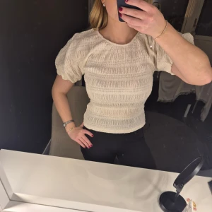 Krämvit puffärmad blus - Helt oanvänd. Krämvit blus med puffiga korta ärmar och smockad struktur. ❣️