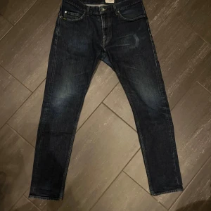 Mörkblå jeans Pistolero 33/34 - Säljer ett par snygga mörkblå jeans från tiger if Sweden i storlek 33/34. Jeansen har modell pistolero. Färgen är en djup mörkblå nyans som passar till de mesta. De är i gott skick, däremot med slitage från en snusdosa och plånbok bild 4/5. Nypris 1600kr