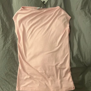 Ljusrosa ärmlös topp från 157 XS - Säljer en ljusrosa, enkel och stilren topp från lager 157 i storlek XS. Toppen är ärmlös med rak halsringning och tillverkad i mjuk bomull. Perfekt för dig som gillar minimalistisk och clean look. Taggen sitter kvar!
