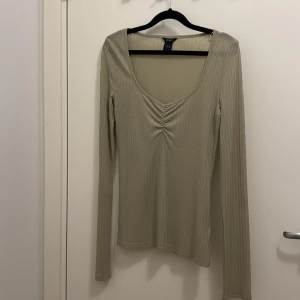 Ljusgrön ribbad långärmad topp Lindex - Säljer en ljusgrön ribbad långärmad topp från Lindex i storlek M. Toppen har en snygg v-ringning med rynkdetalj framtill och är figurnära i modellen. Perfekt att styla med jeans eller kjol för en clean look. Säljer likadan topp i vitt.