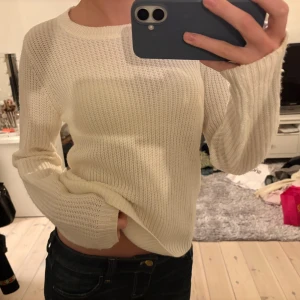 Vit stickad tröja med rund hals - Säljer en vit stickad tröja med rund halsringning och långa ärmar. Tröjan har en enkel, ribbad struktur och är perfekt för lager-på-lager. Passformen är normal och materialet känns mjukt och skönt mot huden.