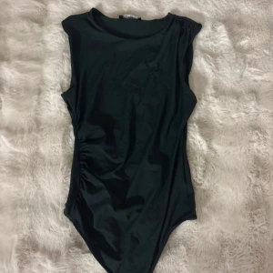 Svart bikini med hög hals - Snygg svart bikini med hög hals och breda axelband. Enkel och stilren design utan mönster eller detaljer, perfekt för dig som gillar minimalistiskt. Materialet känns mjukt och följsamt mot huden, och modellen har en tight passform som framhäver figuren.