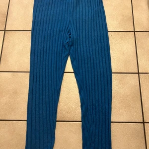 Blå ribbade mjukisbyxor storlek 2XL - Säljer ett par blå mjukisbyxor med ribbad struktur. Byxorna har elastisk midja och är tillverkade i ett mjukt material som känns skönt mot huden. Perfekta för chill dagar hemma eller när du vill vara extra bekväm.