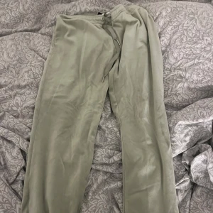 Gröna mjukisbyxor med snörning - Säljer ett par chill gröna mjukisbyxor med snörning i midjan. De har en loose passform och är gjorda i mjukt syntetmaterial som känns skönt mot huden. Perfekta för att hänga hemma eller dra till gymmet i.