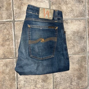 Nudie Jeans  - Snygga blå Nudie Jeans Skinny Lin. Jeansen har smal passform, normal midja och är tillverkade i stretchig bomullsdenim. Midja 39cm, längd 93cm. OBS Uppsydda för att passa L30 men utgå ifrån måtten :) JAG SKICKAR EJ FLER BILDER NÄR JAG BÄR JEANSEN! för storleksguide hänvisar jag till måtten och för bättre inblick i passformen rekommenderar jag att googla på modellnamnet. Jeansen kan vara uppsydda utan att jag noterat det så kolla måtten noggrant :) s4 