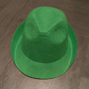 Grön filthatt med klassisk form - Säljer en cool grön hatt i filtmaterial med klassisk form och uppvikt brätte. Perfekt för dig som vill sticka ut med en färgstark accessoar. Hatten har en mjuk känsla och passar till många olika stilar.