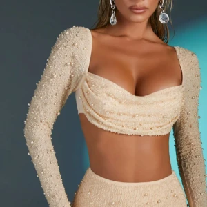 Oh Polly festtop - Säljer en beige croppad topp med långa ärmar, täckt av pärlo från Oh polly. Storlek m. Endast testad. Tröjan är lite mer beige rosa i verkligheten. Storlek 40.