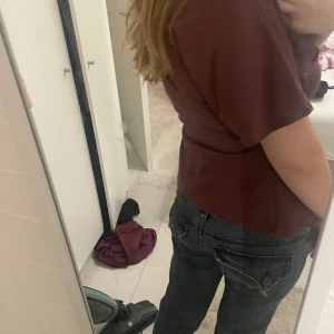 Mörkgrå jeans med raka ben - Säljer ett par mörkgrå jeans med raka ben och snygga detaljerade bakfickor med knappar. Jeansen har låg midja och klassisk femficksdesign. Perfekta för dig som gillar en avslappnad men ändå stilren look. Har skosnöre i midjan så midjan är justerbar. S/M