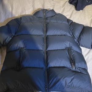 Mörkblå Colmar pufferjacka - Säljer en mörkblå pufferjacka från Colmar Originals med hög krage och två praktiska fickor med dragkedja. Jackan har ett stilrent, quiltat mönster och logotyp på ärmen. Perfekt för kalla dagar och har en modern, loose passform. Jag köpte jackan ny pris för 4500 kr 