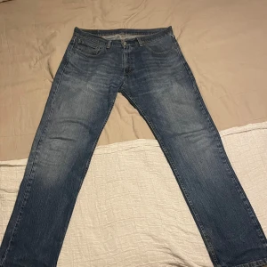 Levi's 505 blå jeans straight fit - Klassiska Levi's 505 jeans i blå denim med rak passform. Tillverkade tidigt 2000-tal. Pågrund av åldern är de väl använda men även väldigt snygg tvätt.  Tecken på slitning finns vid hälen samt en liten fläck som inte går bort i tvätten, jag inte riktigt vet vad det är.  W34 L32                                                             Annars riktigt snygga och stilrena!          Tillverkade i 99% bomull och 1% elastan för lite stretch. Perfekta för dig som gillar tidlös stil. 