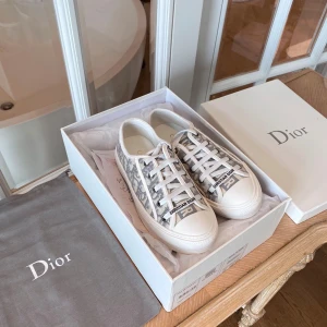 Dior sneakers med monogrammönster - Snygga Dior sneakers i vit och grå färg med ikoniskt monogrammönster. Skorna har rund tå, platt sula och snörning framtill. Materialet är textil med detaljer i skinn och logotypen 'Christian Dior' på tungan. Perfekt för dig som gillar exklusiv streetstyle.BESTÄLLNINGSVARA läs i min profil där står allt!