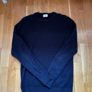 Mörkblå stickad tröja John Henric - Mörkblå stickad tröja från John Henric med diskret kabelstickat mönster. Tröjan är knappt använd 9,5 skick. Storlek L men den passar mig som har M. Hör av er vid frågor eller funderingar.