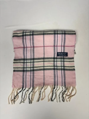 Rutig rosa halsduk från Burberrys - Snygg halsduk i rosa med klassiskt rutmönster från Burberrys. Halsduken har fransar i ändarna och är tillverkad i 100% lammull. Perfekt accessoar för att lyfta din outfit med en touch av lyx och färg.