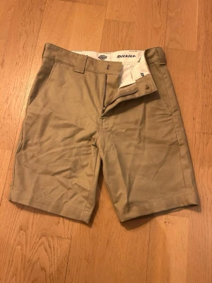 Beige shorts från Dickies - Är du en grabb som gillar lite schysstare kläder till ett riktigt fett pris så är det här ditt plag snart, skulle säga att de passar lite mer åt skater hållet för märket osv. Men dom sitter inte baggy bara allmänt soft! Frågor? Kom in och ställ dom!