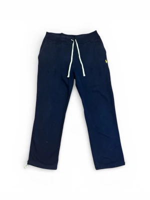 Marinblå mjukisbyxor från Polo Ralph Lauren - Mysiga marinblå mjukisbyxor från Polo Ralph Lauren med vit dragsko i midjan och gul broderad logga på benet. Byxorna har raka ben och är tillverkade i mjukt material som passar perfekt för chill dagar. Befintligt skick