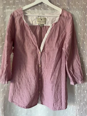 Ljuslila blus från Maison Scotch - Söt ljuslila blus från Maison Scotch med knappar framtill och lätt rynkad struktur. Blusen har trekvartsärm och en avslappnad passform. Tillverkad i ett tunt, mjukt tyg som känns luftigt och bekvämt. Djur och rökfritt hem. Jag skulle säga lite stor i stl. 