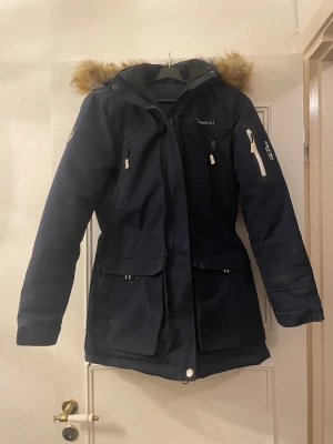 Rosetti riding ridjacka/vinterjacka, storlek 38 - Rosetti riding ridjacka/vinterjacka, storlek 38. Ena delen av resåren har lossat lite, stör ej funktionen, går fortfarande att dra åt i midjan. Som man ser på bilden lägger jag den lösa delen ner i fickan istället för in i hålet där den egentligen ska sitta fast. Knappt använd, dock lite damm som lätt går att torka bort.