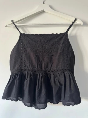 Svart broderad linnetopp med volang från Zara - Jättefin Svart linnetopp med tunna axelband, broderade detaljer framtill och volang nertill. 😍