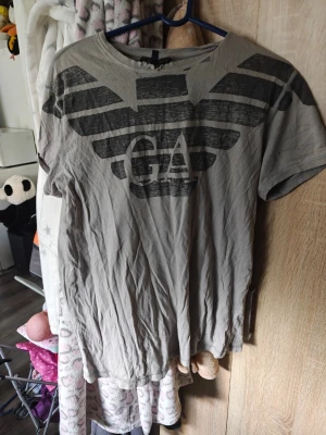 Grå t-shirt från Armani med tryck - Snygg grå t-shirt från Armani med stort svart logotryck på bröstet. Klassisk rund halsringning och korta ärmar. Perfekt för en avslappnad och trendig stil.